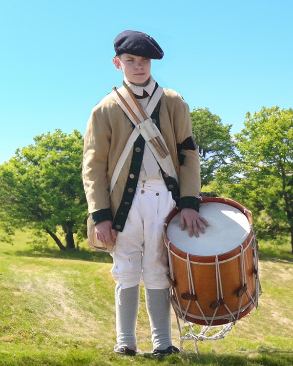 A young man in a soldier's uniform carries a large drum at his waist.