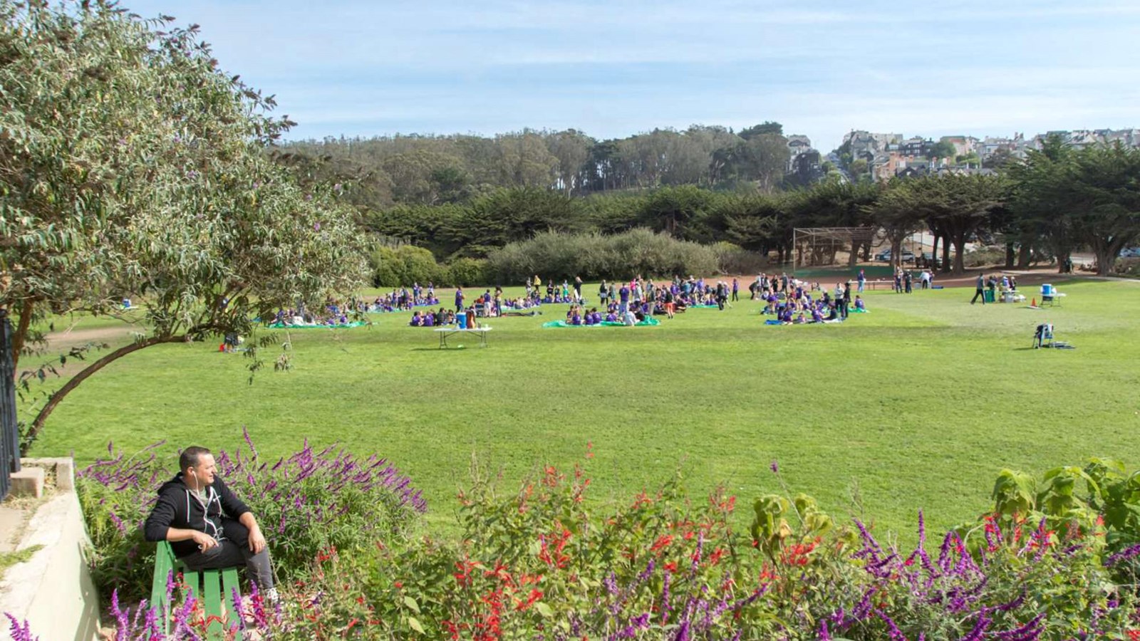 Bright green grass of an open field filled with people playing sports.