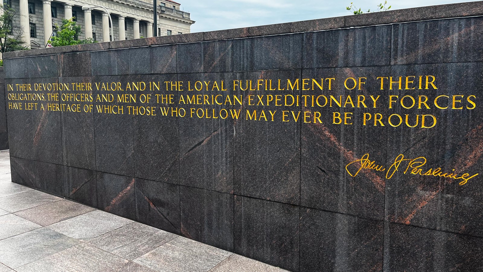 A dark stone wall features yellow lettering
