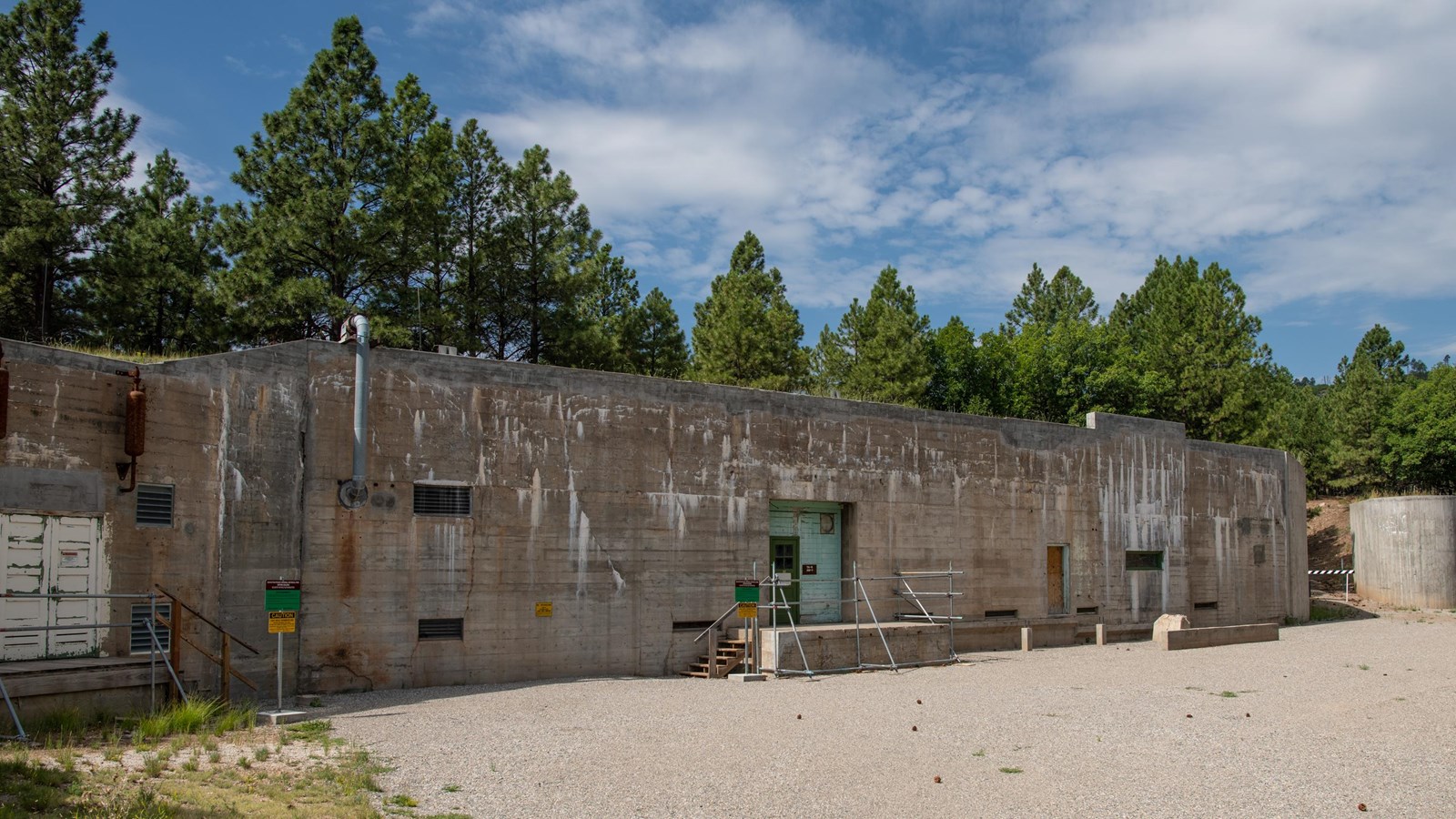 A long building made of gray stone sits next to a smaller, rounded gray structure.