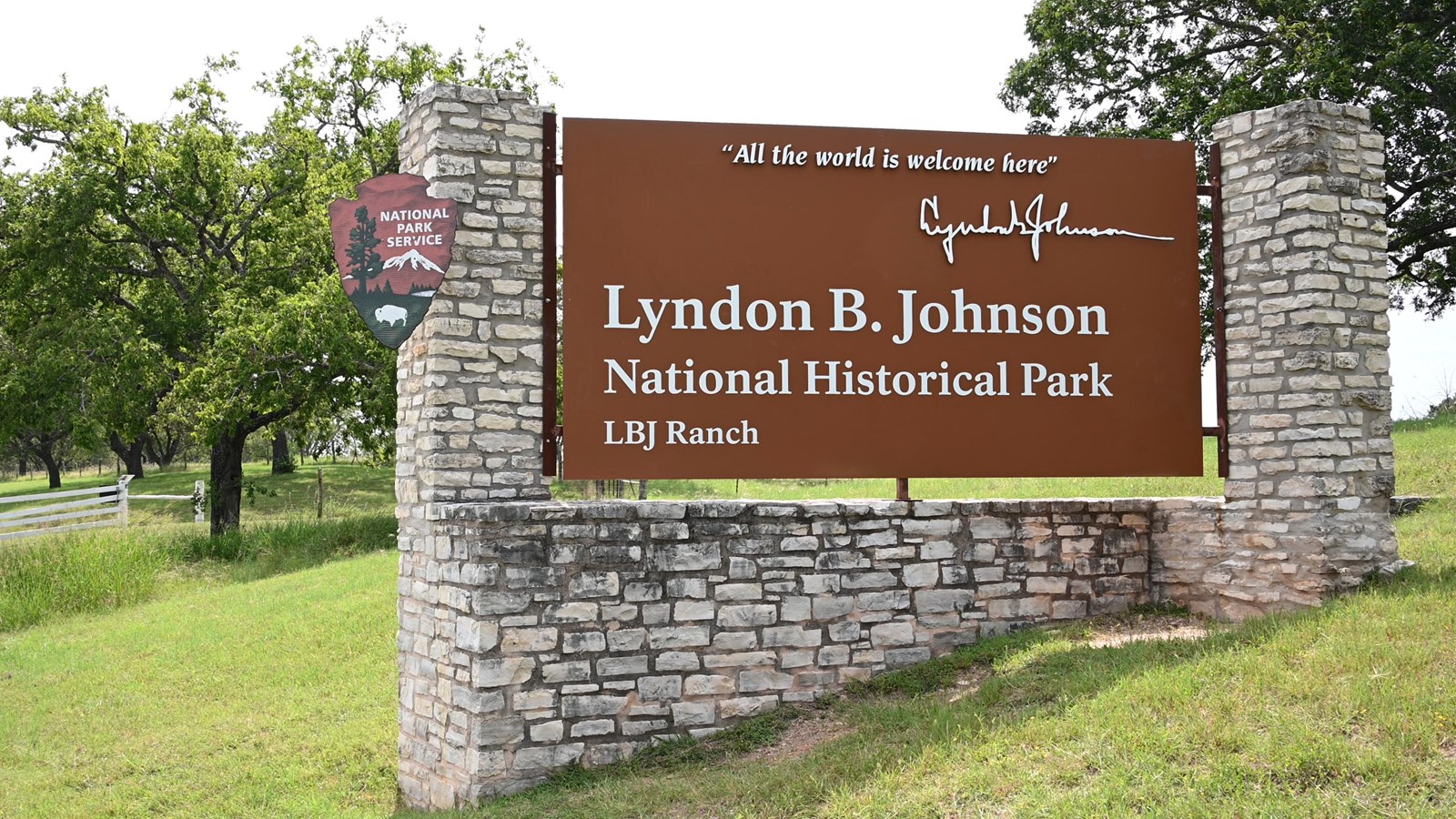 A wood and stone sign in front of a Live Oak tree.