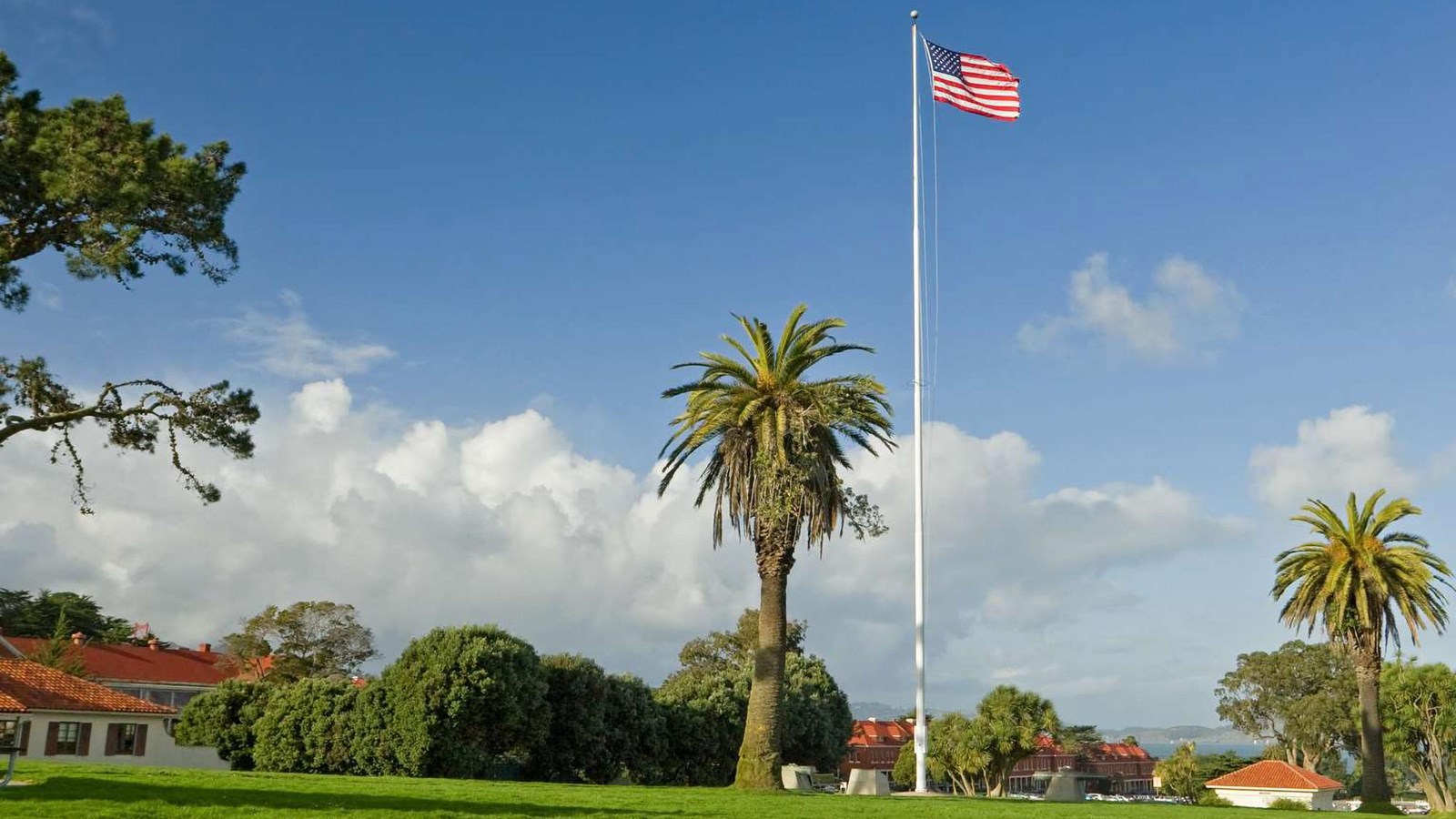 Green grass lawn of Pershing Square with blue skies and US flag waving in the wind.