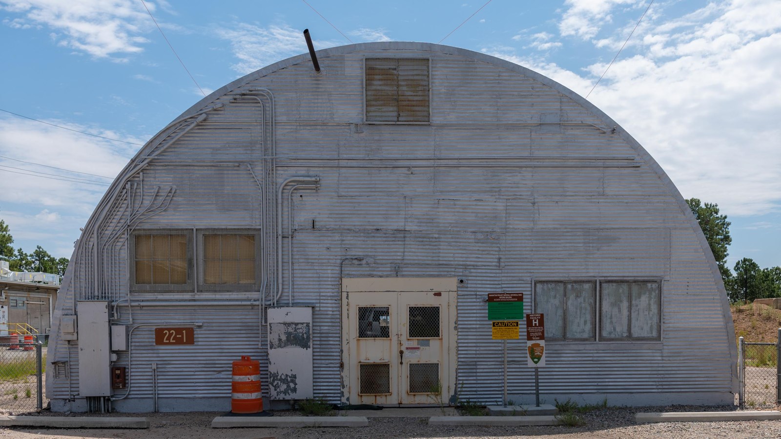The semi-circular end of a large metal building with doors and windows.