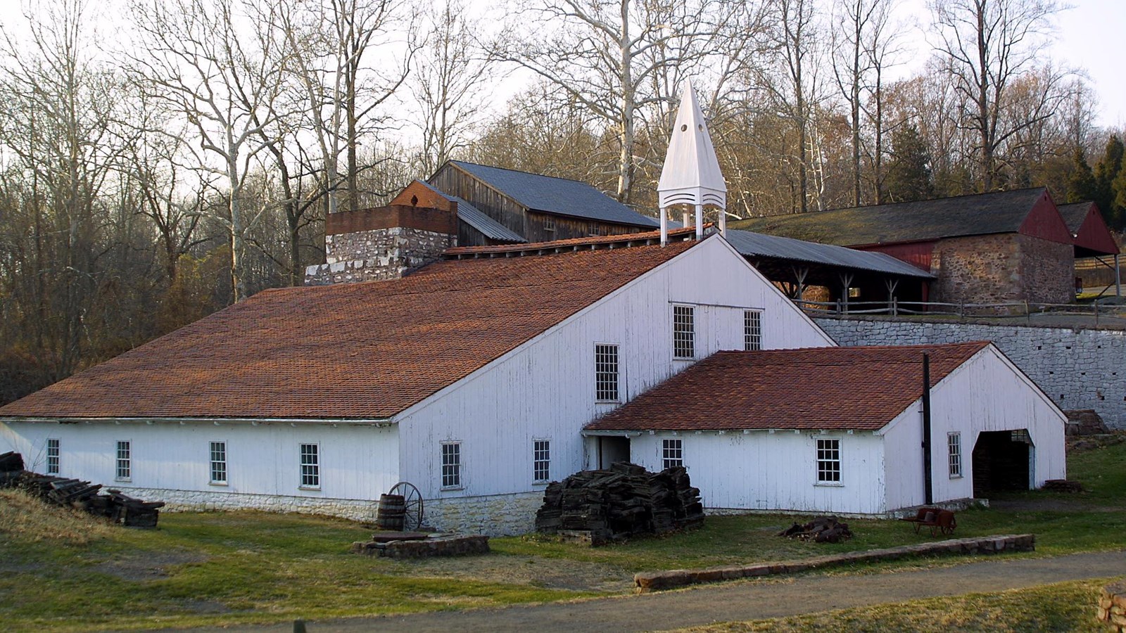 View of large one story historic white building with red slate roof and bell steeple