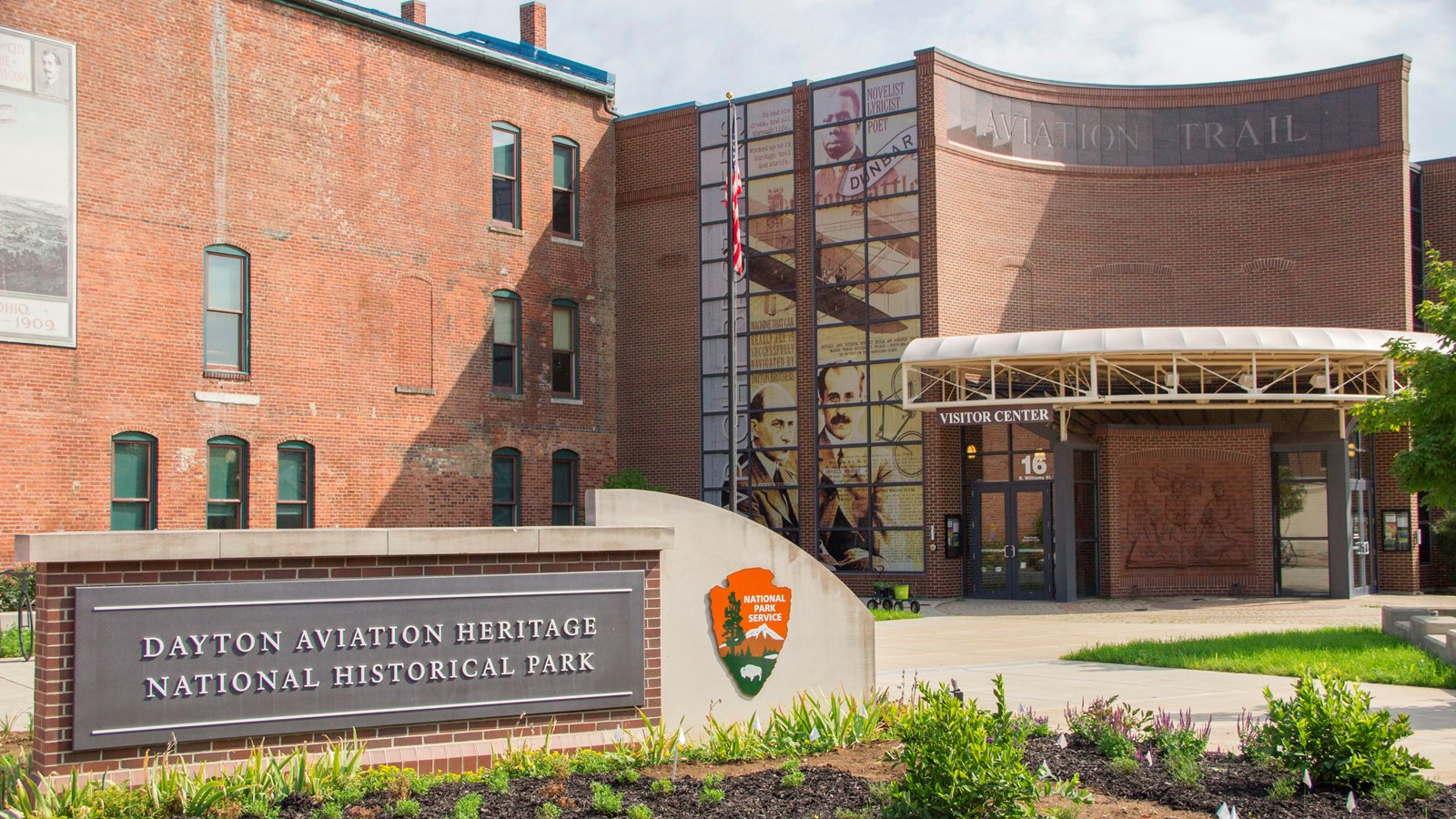 A large, two-story brick building with a sign out front reading Dayton Aviation Heritage NHP