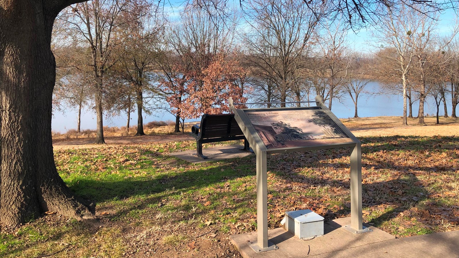 Wayside and bench overlooking the Arkansas River and leafless trees on a clear winter day.