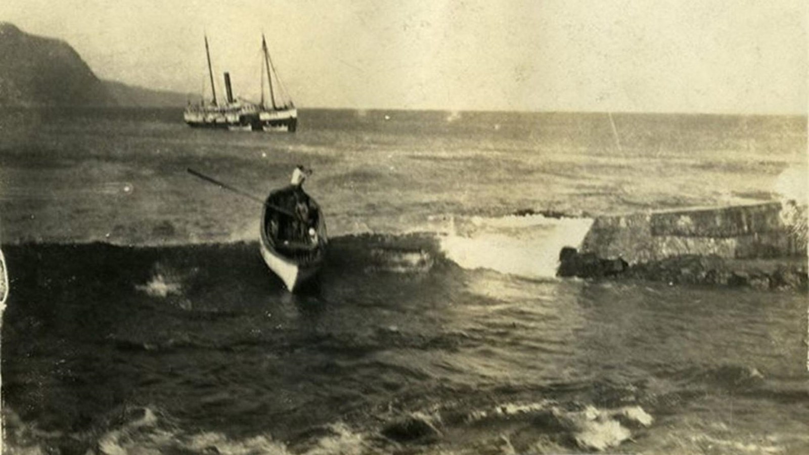 A historic picture of a rowboat on a cresting wave as it arrives at Kalaupapa