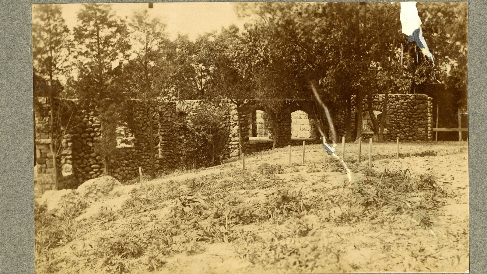 Black and white of stone ruins looking like a building on grassy hill