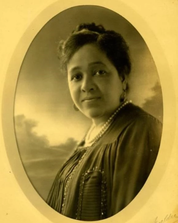 Sepia toned photograph of an African American women from the chest up. She is looking at the camera.