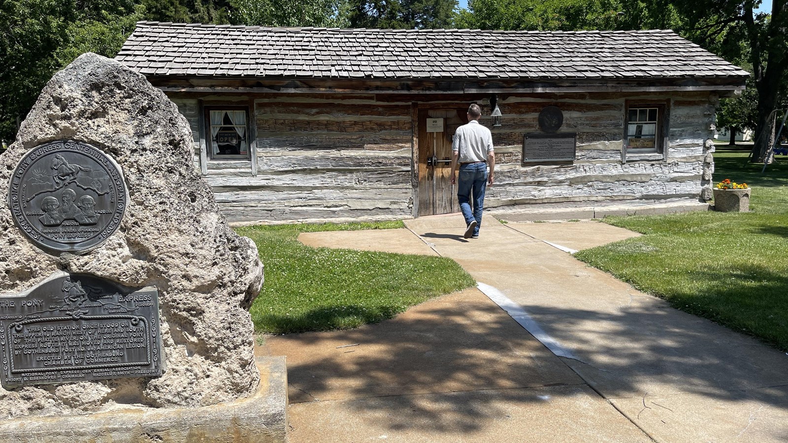 A historic one room log cabin in a park.