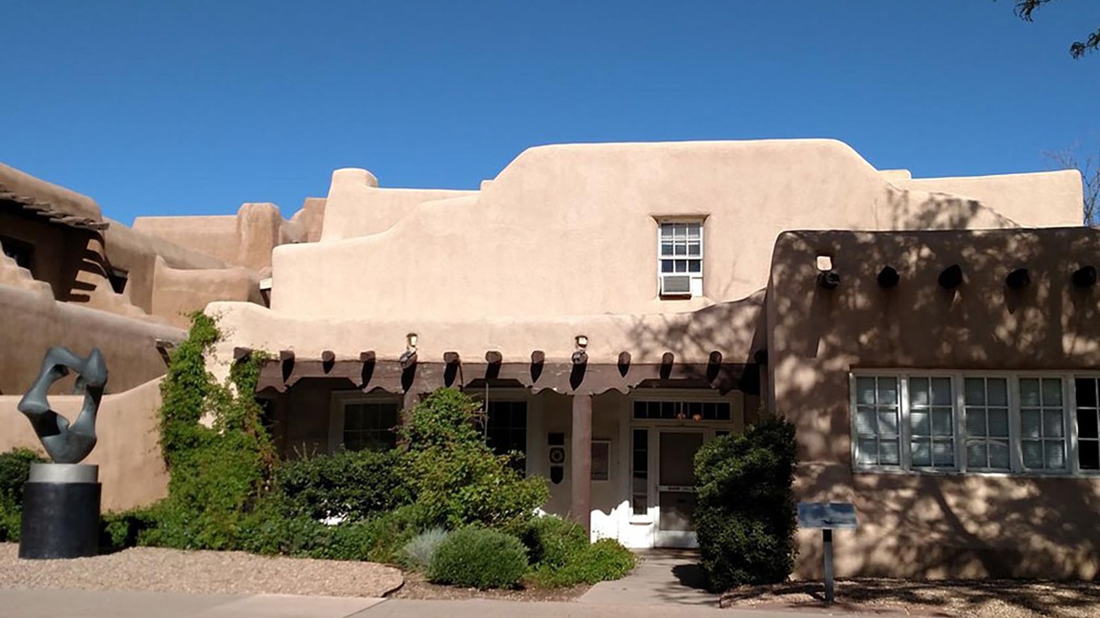 The front of an adobe building with a wooden porch.