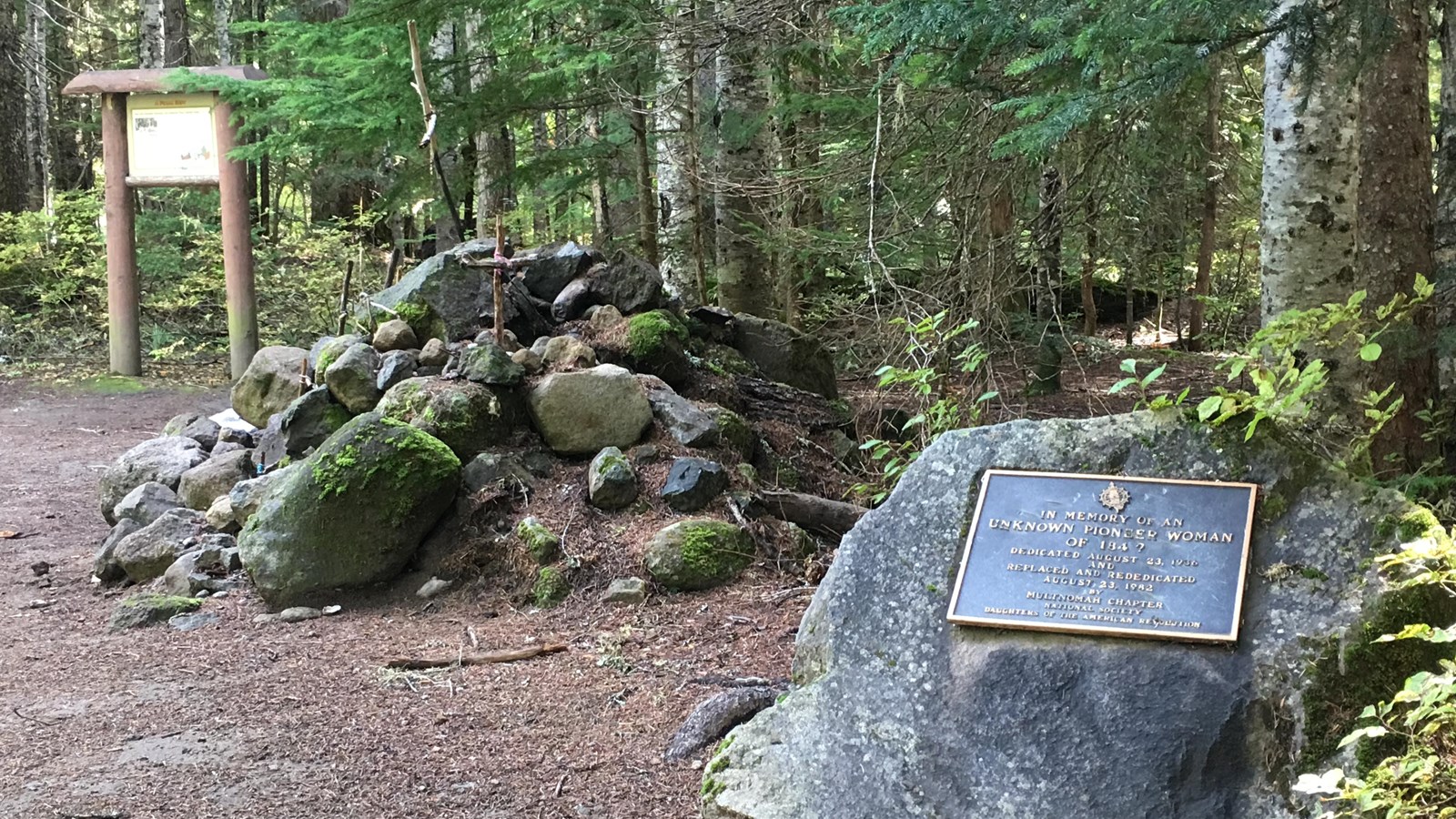 A rock monument sits next to a pile of rock in a forest.