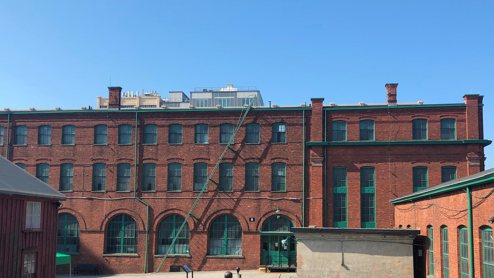 Long, rectangular, three story, red brick building. Sky, courtyard, statue surround.