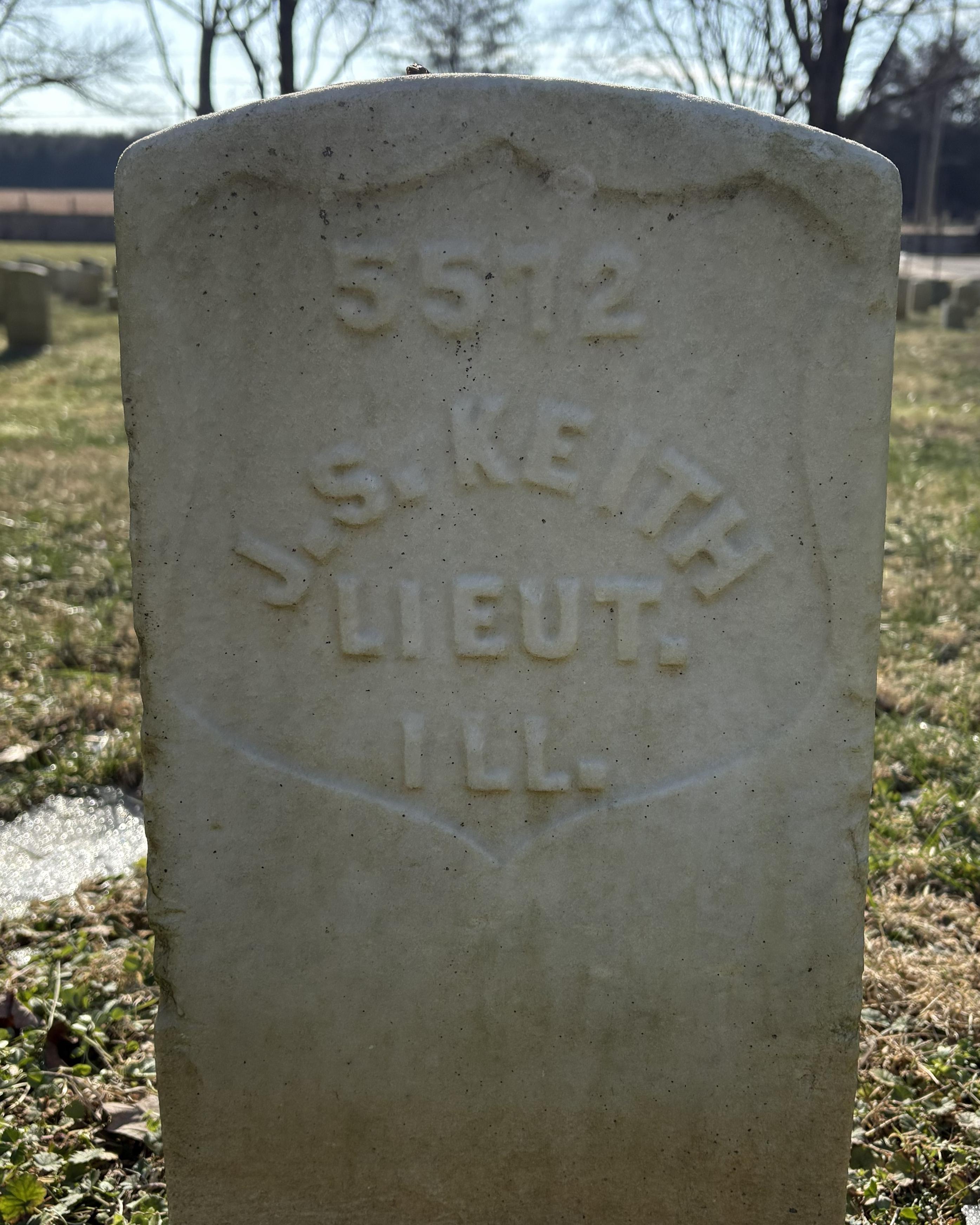Marble headstone with grass and trees around it.