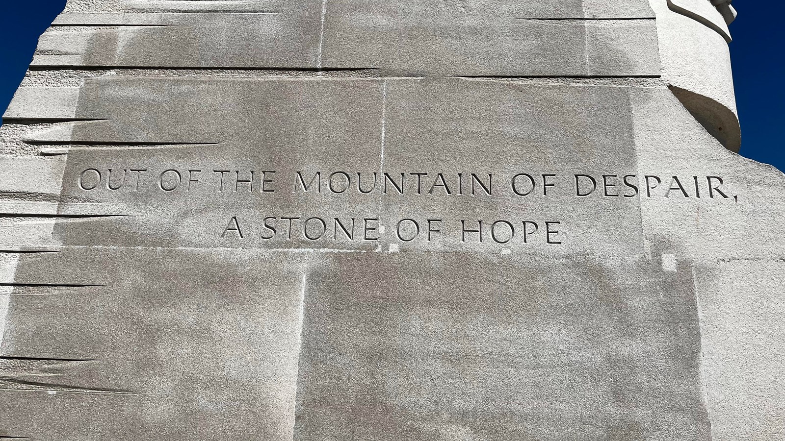 Large light colored stone with a quote etched into its side