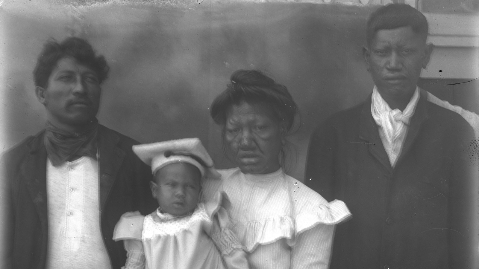 A family of four, including on infant, pose for a photo in the early 1900s