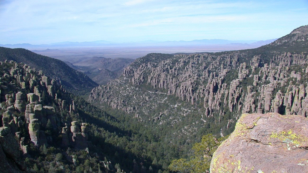 Green valley in distance lined with rock pinnacles