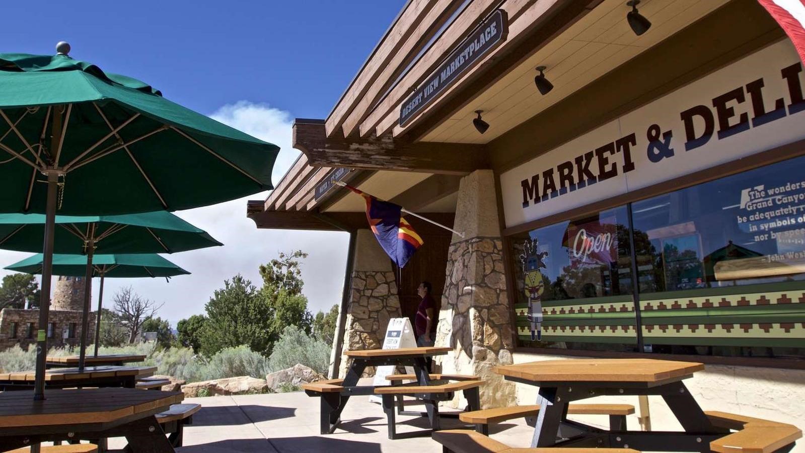 A brown and white building with picnic tables out front with green umbrellas