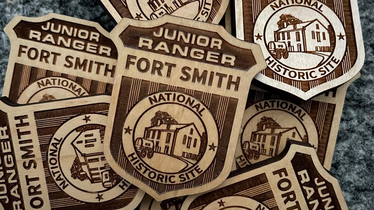 Wooden Junior Ranger badges with text reading Junior Ranger Fort Smith National Historic Site.