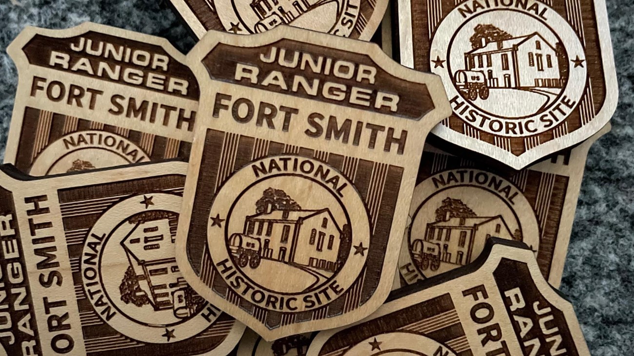 Wooden Junior Ranger badges with text reading Junior Ranger Fort Smith National Historic Site.