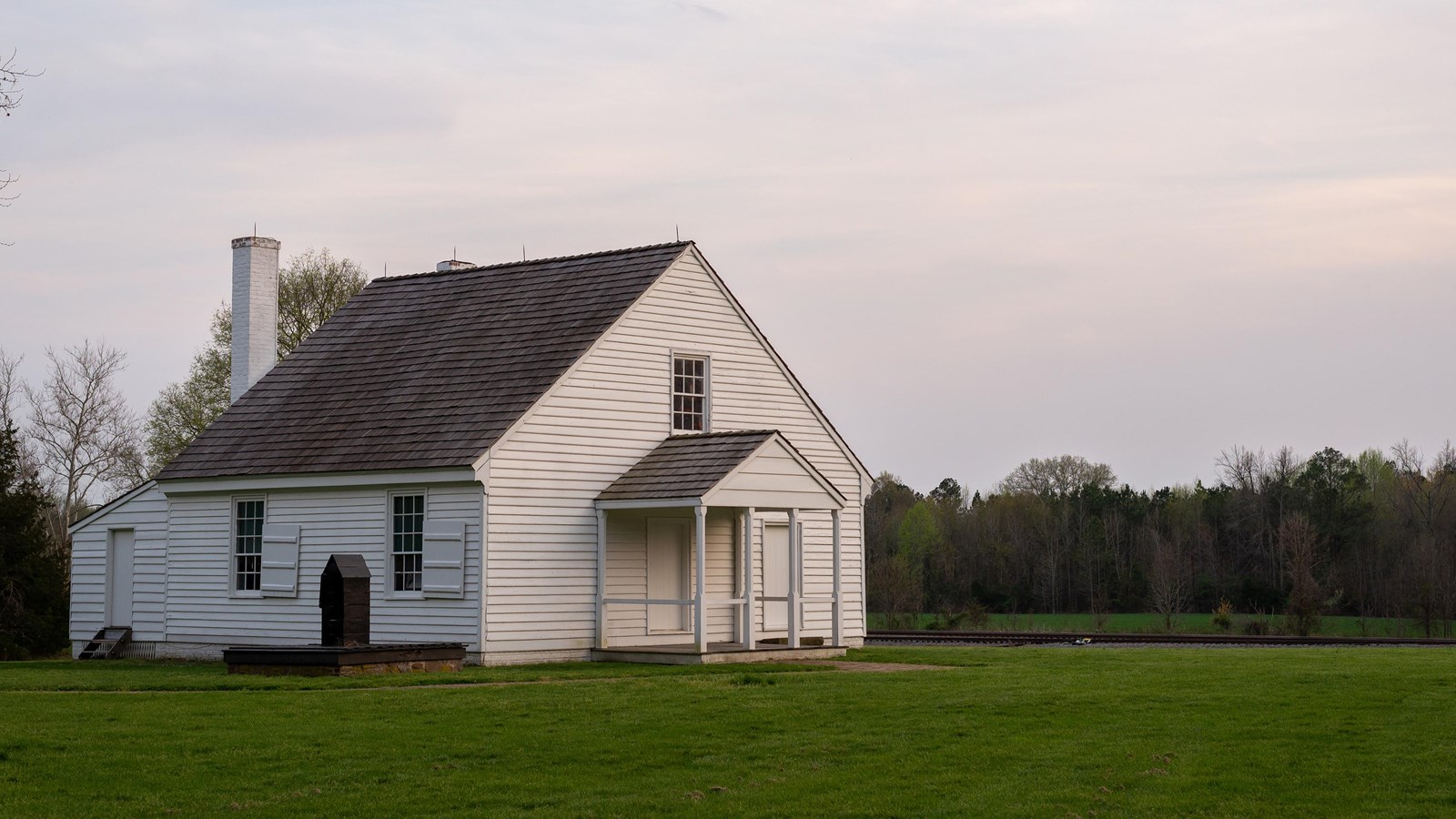A 1.5 story white house in a mowed lawn.
