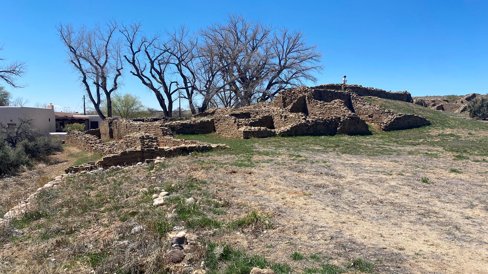The remnants of sandstone walls extending one to two stories from the ground under a bright blue sky