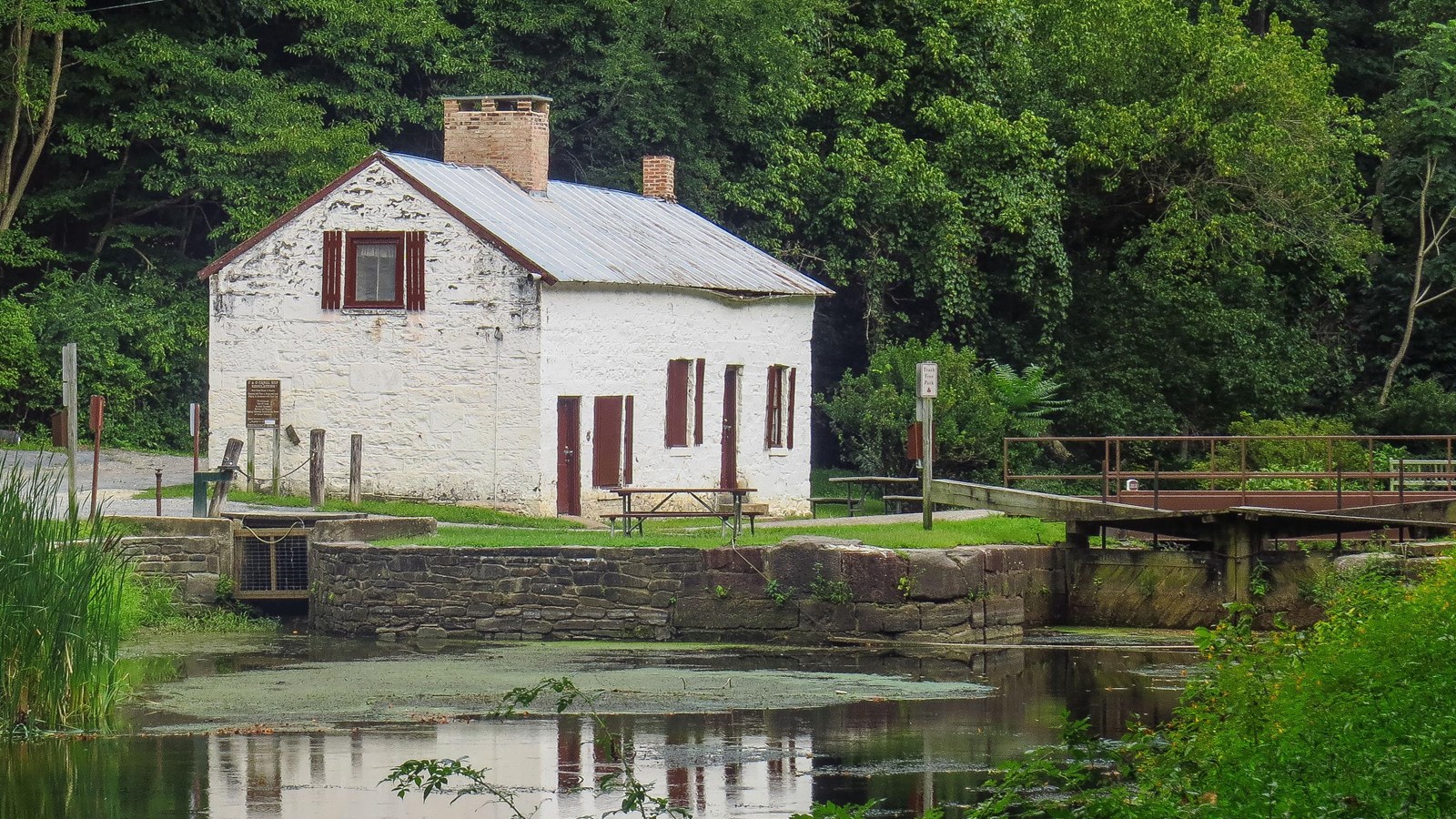 A white lockhouse sits on the far side of a watered canal.