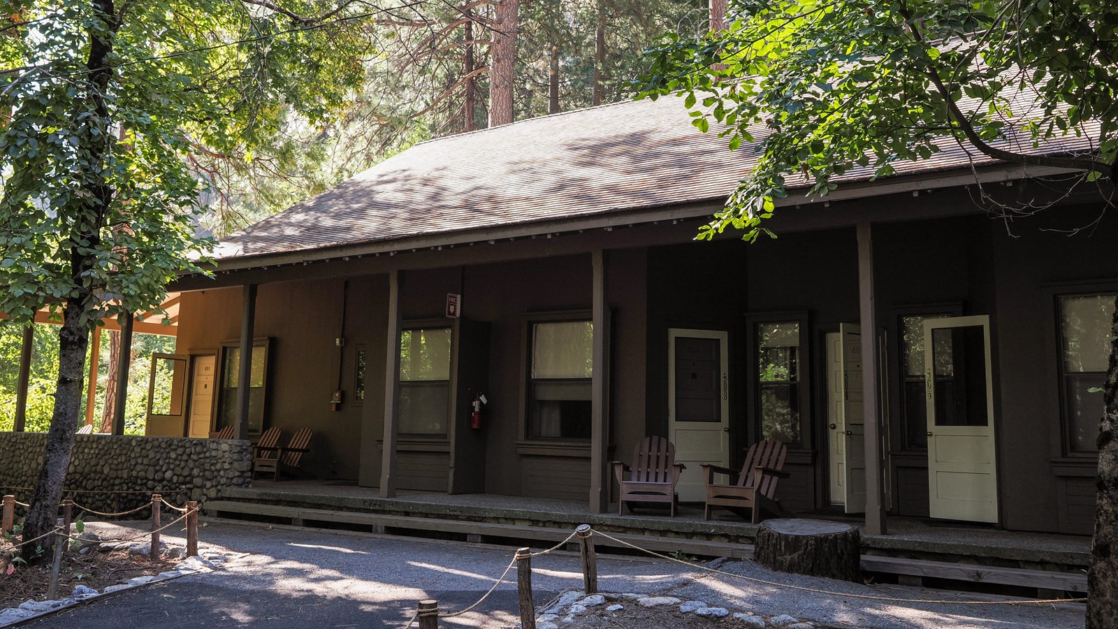 A single story building with a covered porch and several doors to guest rooms