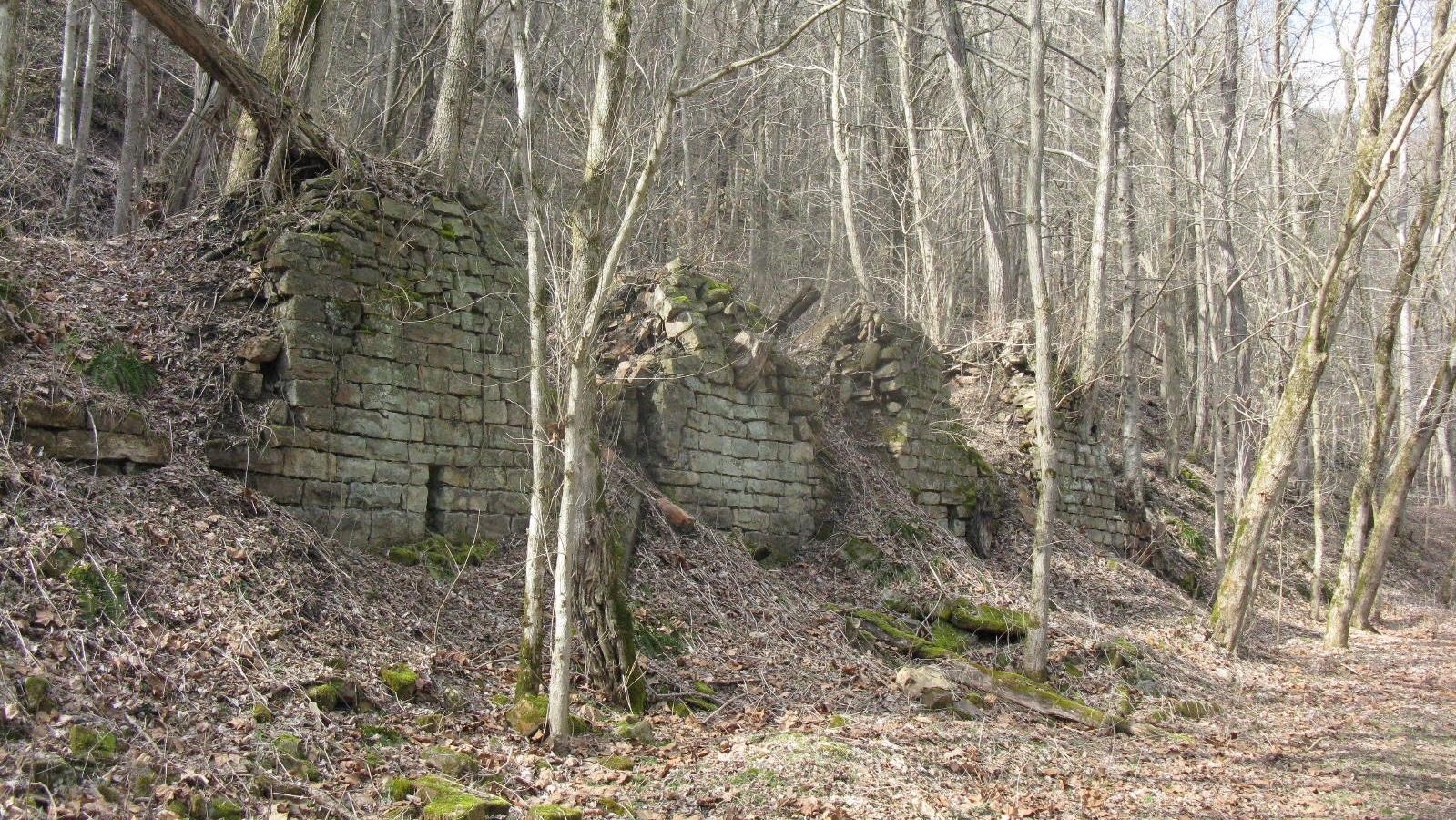 Brick beehive shaped mounds sit to the left of the trail among barren trees.