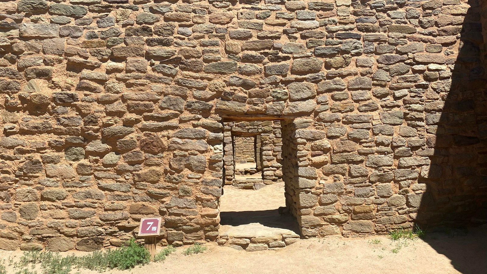 A series of stacked sandstone walls with openings in a straight row.