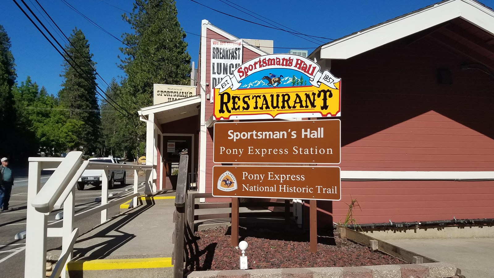 A sign for Sportsman’s Hall restaurant and Pony Express station stands at the end of a red building.