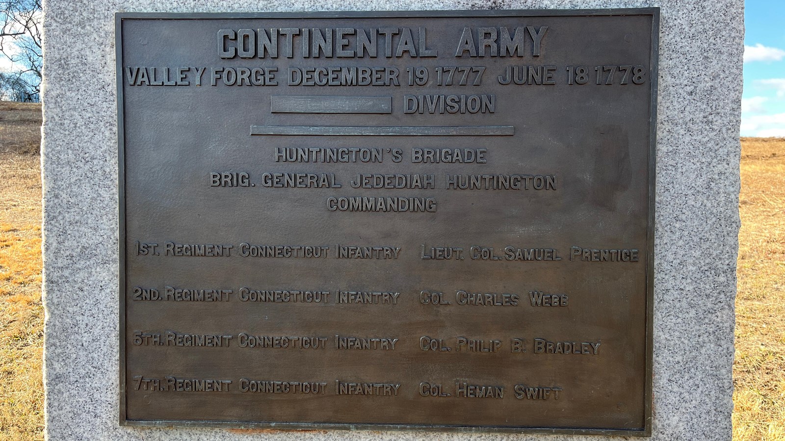 A granite slab monument with a bronze plaque mounted on the front.