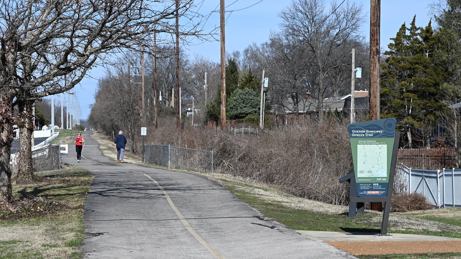 paved trail with green sign and runners