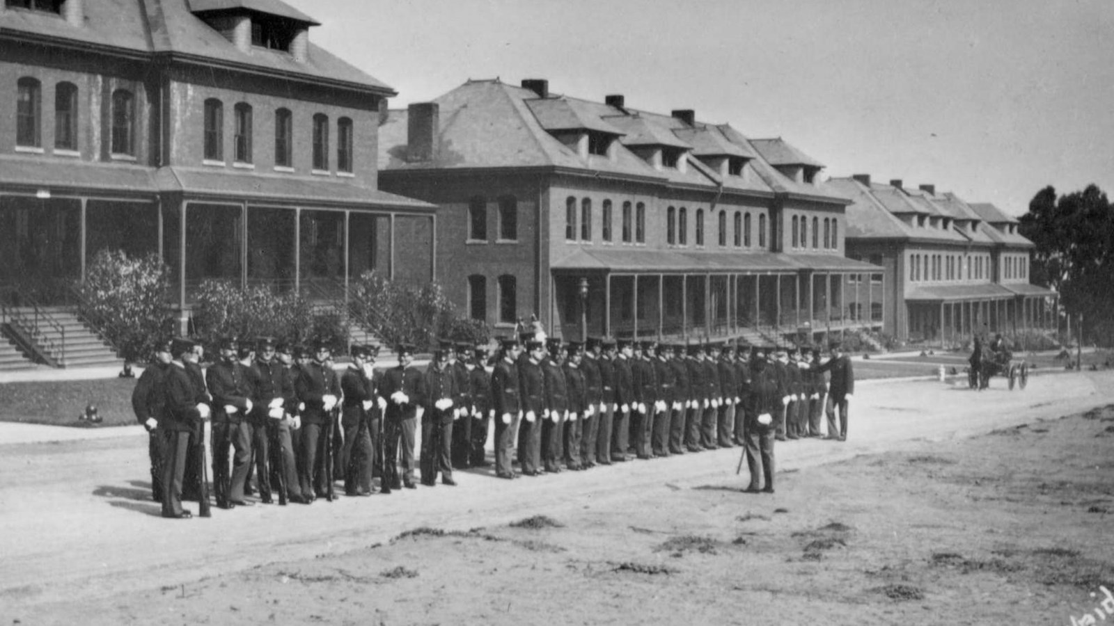 Black and white photograph of a line of soldiers in two rows as another man inspects them.