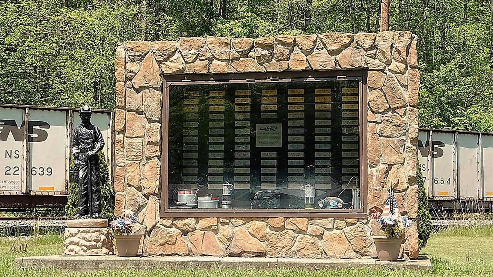 A memorial with statue of coal miner with train cars behind