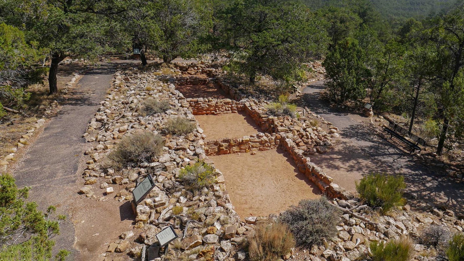 Aerial view of footpaths on either side of a row of rectangular shaped rooms outlines.