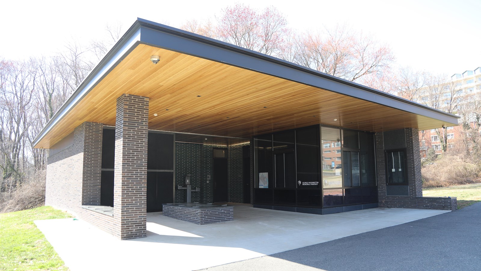 A single story building with a large overhang, benches underneath in front of doors to restrooms.