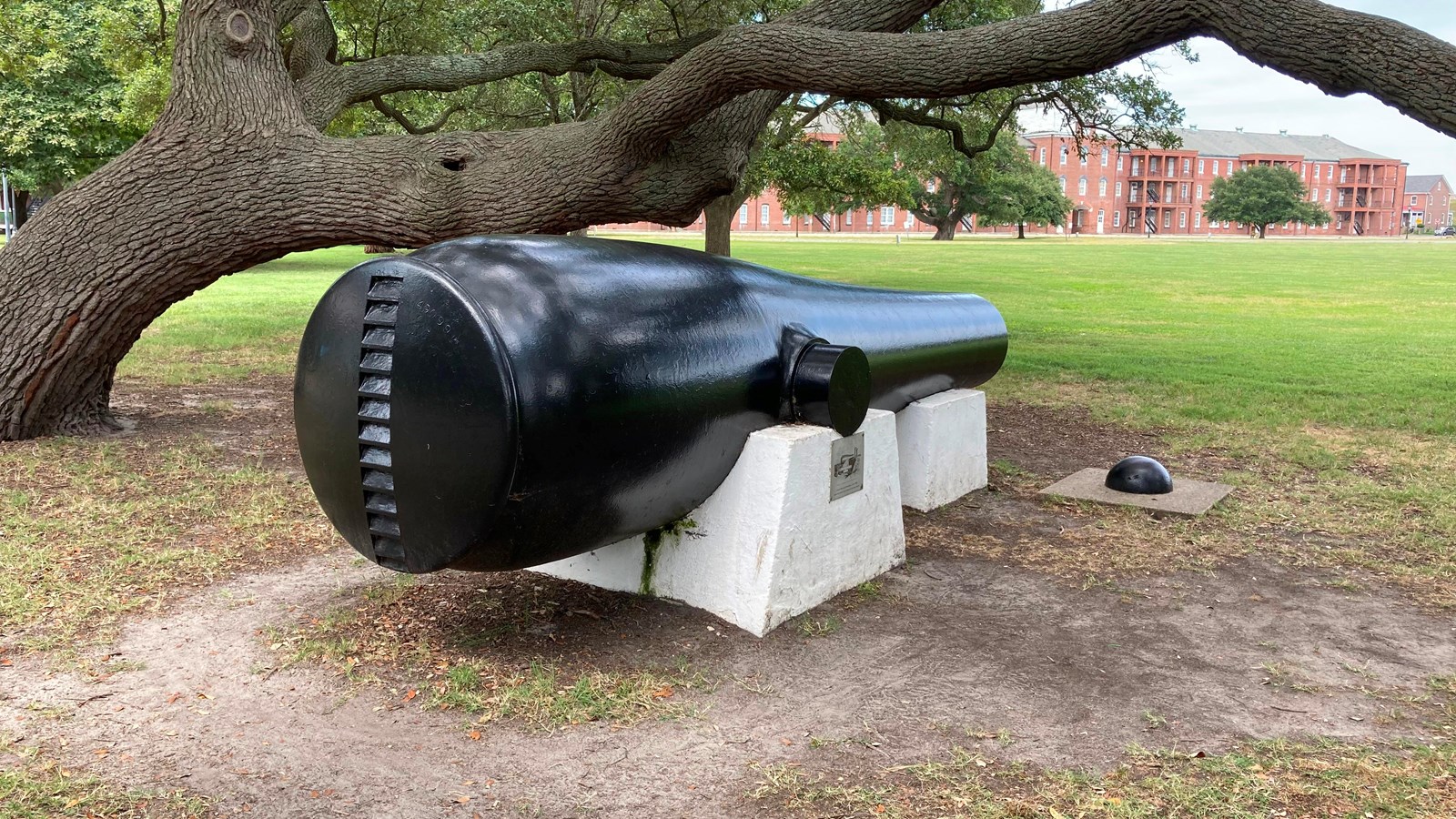 A large, black cast iron cannon is displayed on two white concrete pedestals. 