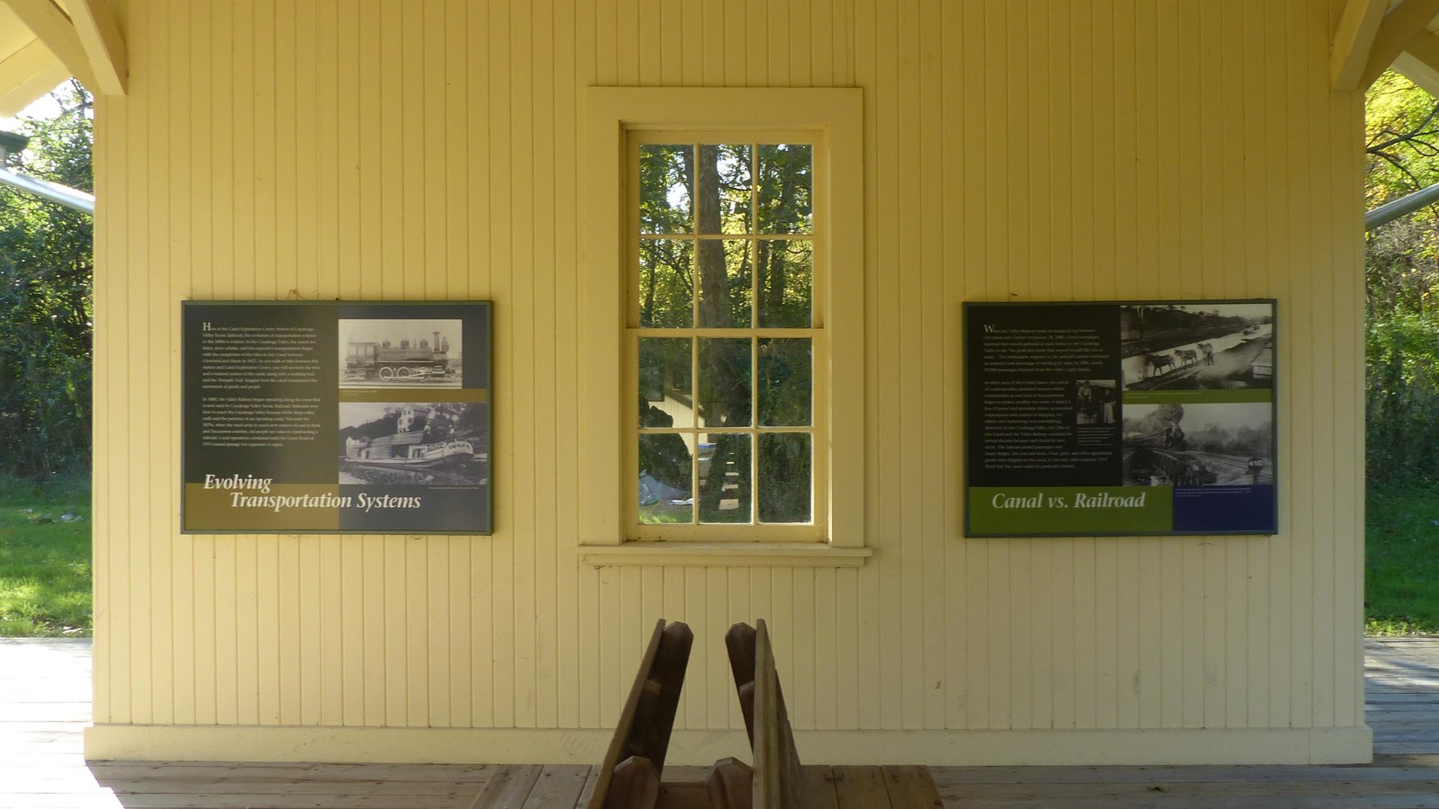 Interior wall of a yellow shelter with two graphic panels on either side of a window.