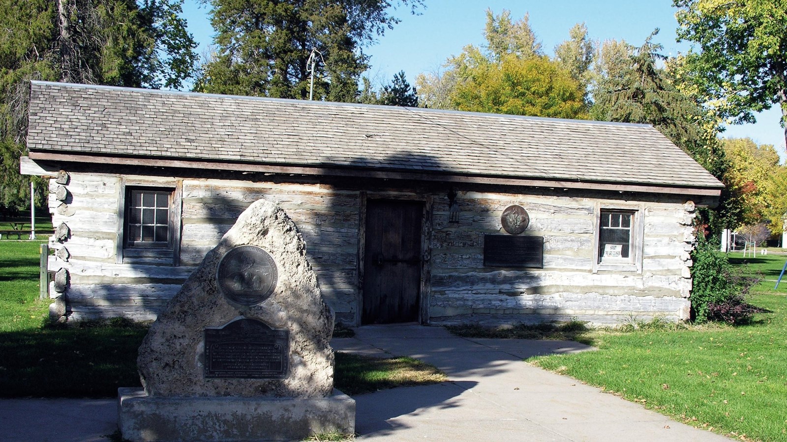 A historic one room log cabin in a park.