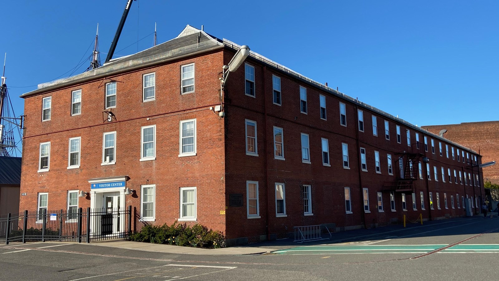 Red rectangular brick building, 3 stories tall, 5 windows across short side, 21 windows on long side