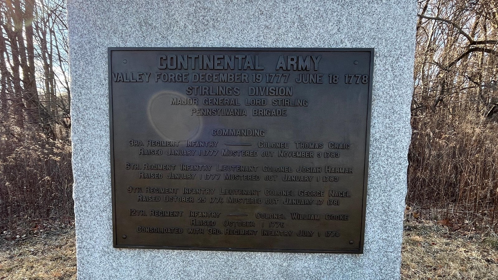 Photograph of a granite slab monument with a brass plaque mounted on the front