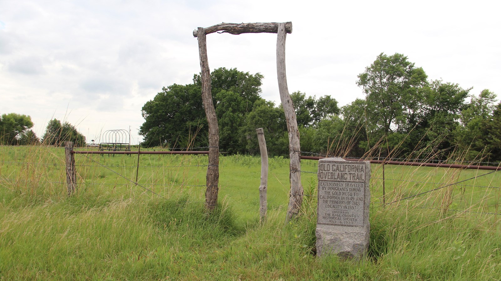 Fence and wood entryway at the Murdock Ruts. Stone marker with text 
