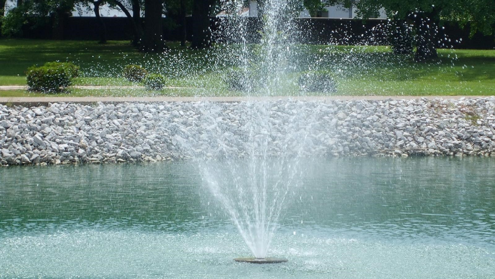 Waters spray from a founting in the center of a rock lined pool