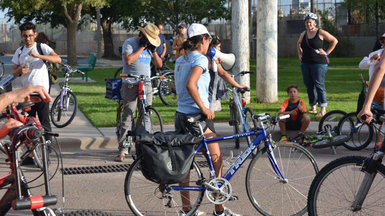 A Chamizal National Memorial intern gives directions to a group of people on bikes.