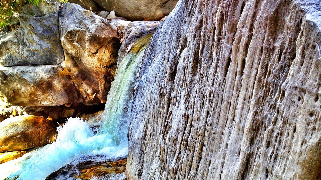 A large waterfall cascades over a marble rock face.