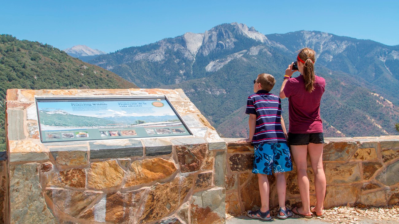 Visitors look out towards a large mountainous landscape.