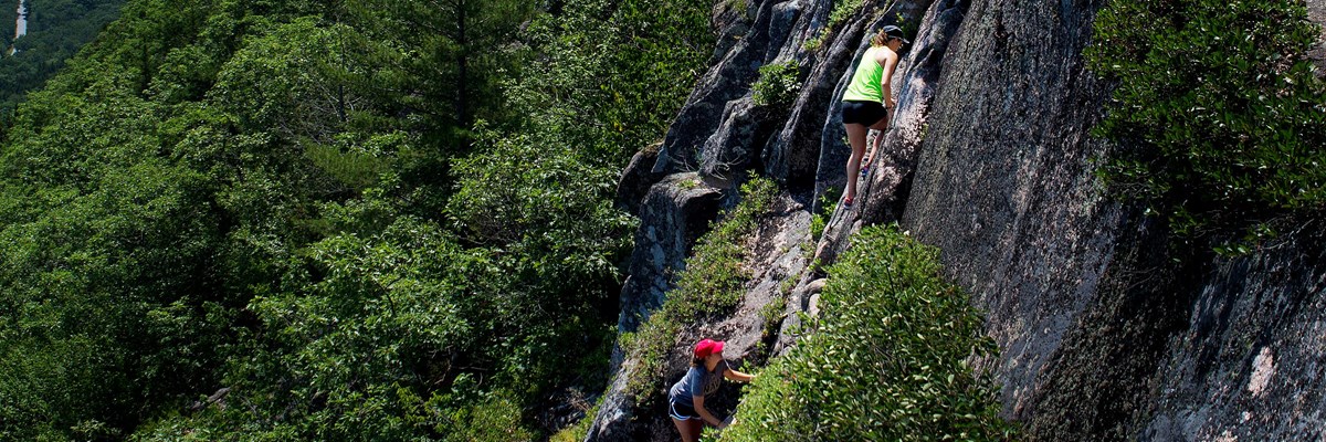 Hikers ascend a cliff with iron rungs