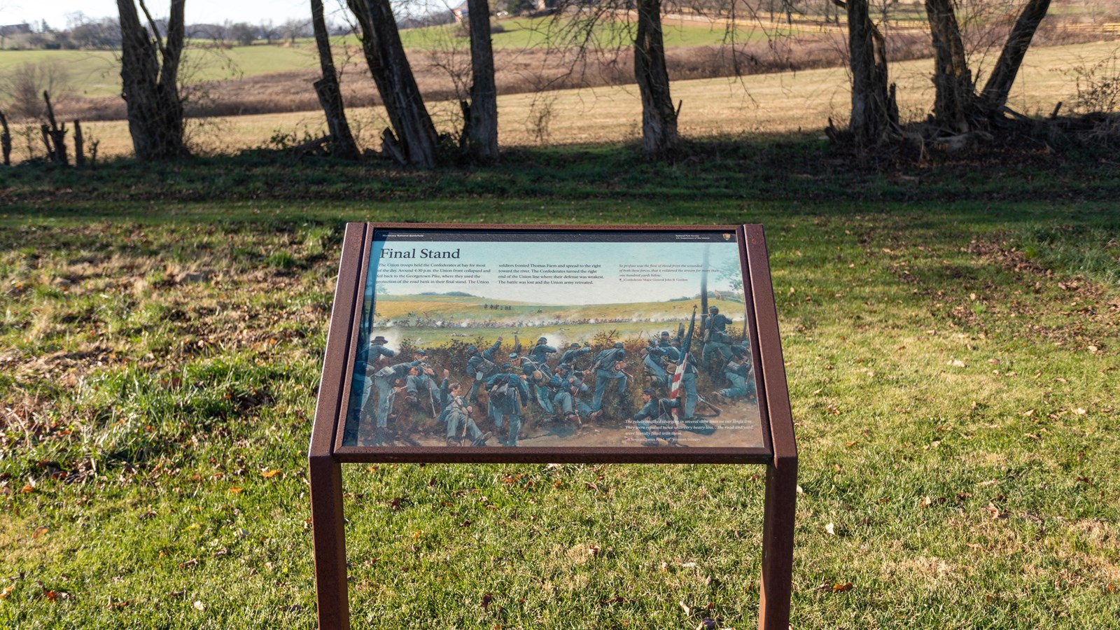 An information panel in front of a grassy field.