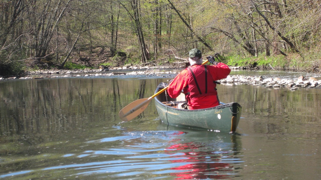 Man in a green canoe paddles down the Blackstone River